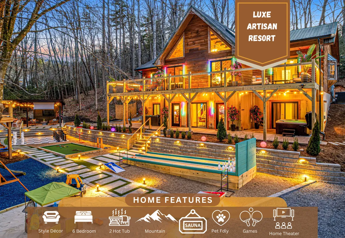 The hero image features a sprawling, beautifully crafted wooden cabin set against lush Black Mountain scenery. The home glows warmly at dusk, with lights illuminating the spacious balcony and inviting outdoor hot tubs. The landscaped yard offers ample space for games, a fire pit gathering area, and inviting views perfect for sunset relaxation.
