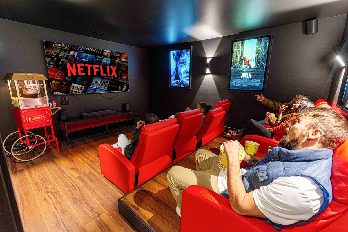 This theater room features red leather recliners arranged before a massive screen displaying the Netflix logo, with movie posters and a popcorn machine adding a classic cinema vibe. The setting is cozy yet immersive—ideal for movie marathons and special screenings.