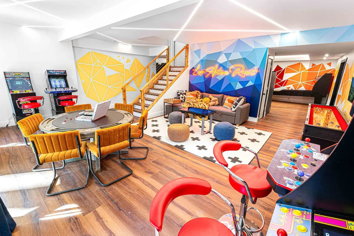 A dynamic arcade and game area is depicted here, with arcade machines, a game table, colorful seating, and playful wall art. The atmosphere is energetic and designed for group fun and interactive entertainment.
