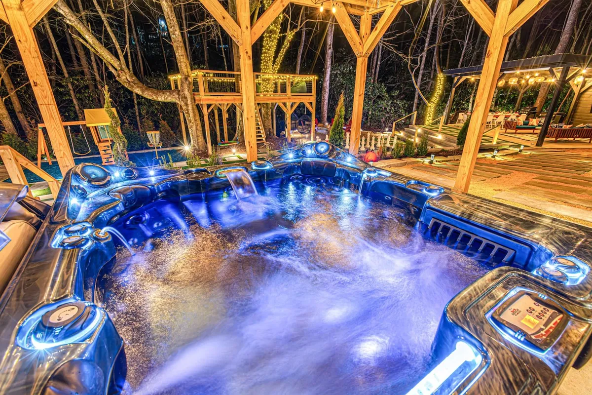 A tranquil hot tub sits beneath ambient lighting on a wooden deck, inviting guests to unwind and stargaze. The setting is luxurious and serene, ideal for soaking after an active day spent exploring the area.