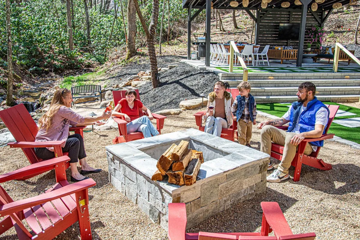 A cozy fire pit area surrounded by Adirondack chairs and greenery, with a covered outdoor space nearby. The inviting setup encourages families and friends to gather, share stories, and unwind after a day of adventures.